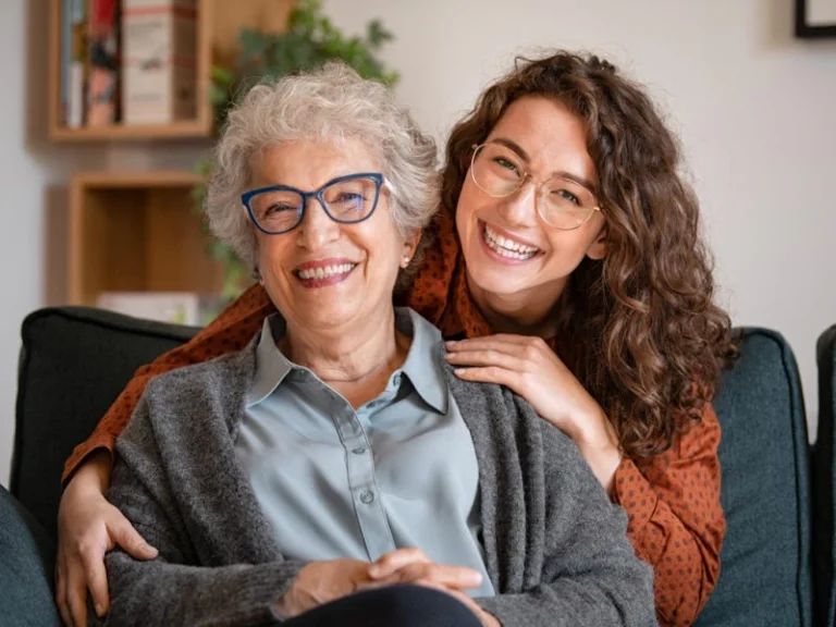 Caregiver providing warm and friendly companion care at home, smiling with an elderly woman