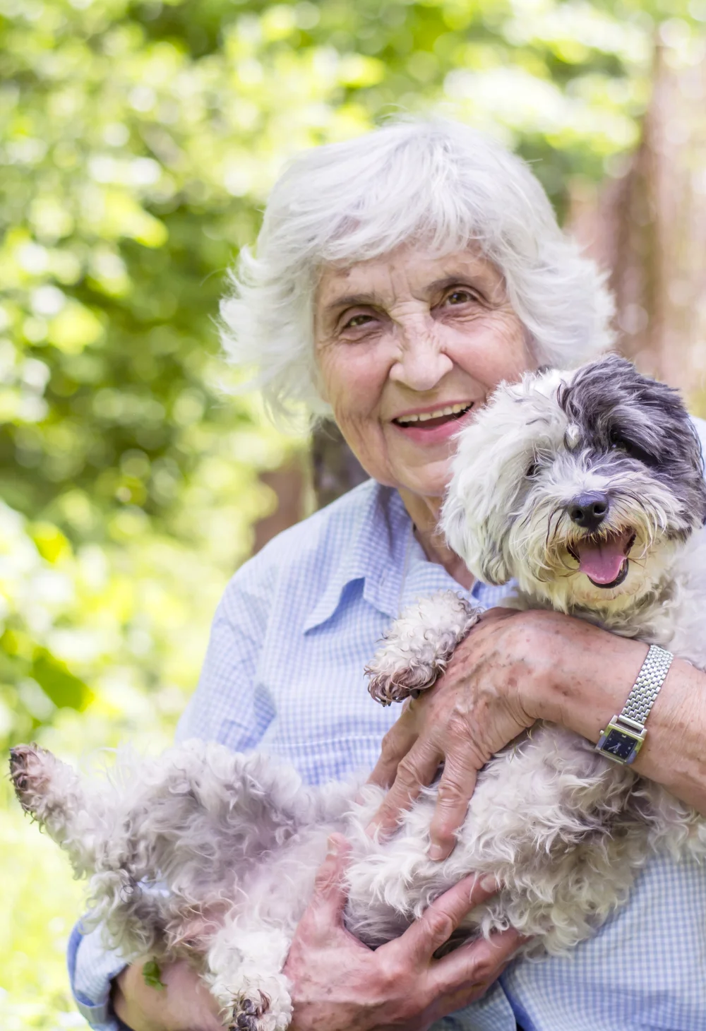 Smiling senior woman holding her small dog outdoors, representing compassionate senior care for Lake Las Vegas residents