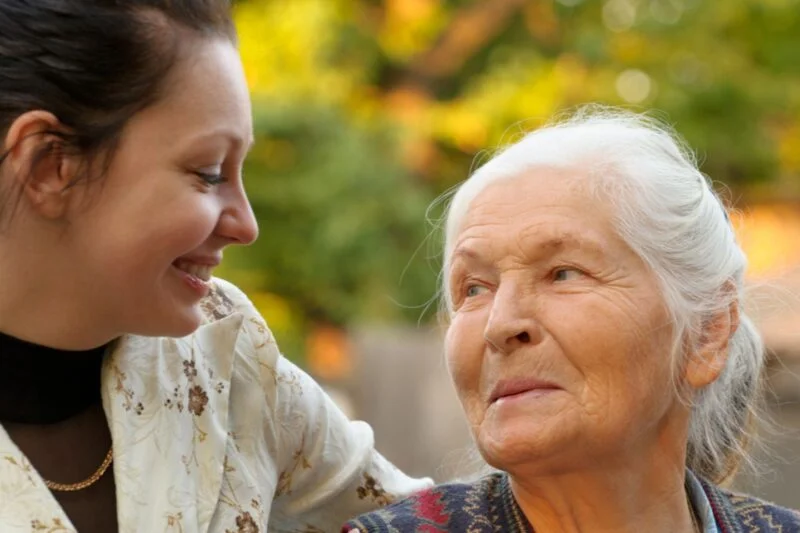 Caregiver smiling warmly at an elderly woman outdoors, representing compassionate senior home care in Southern Highlands Nevada