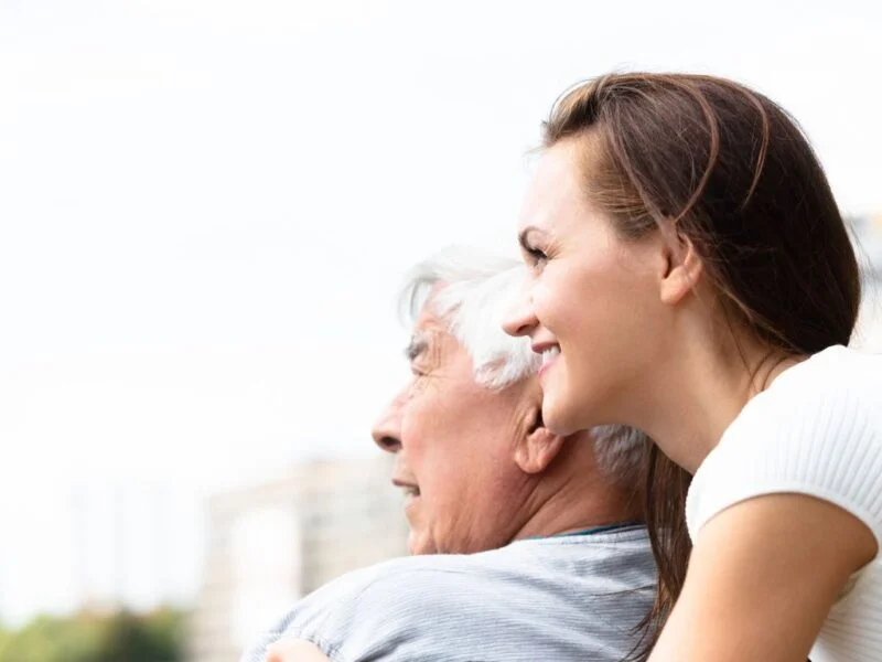 Caregiver smiling while supporting an elderly man outdoors, representing compassionate senior home care in Spring Valley Nevada