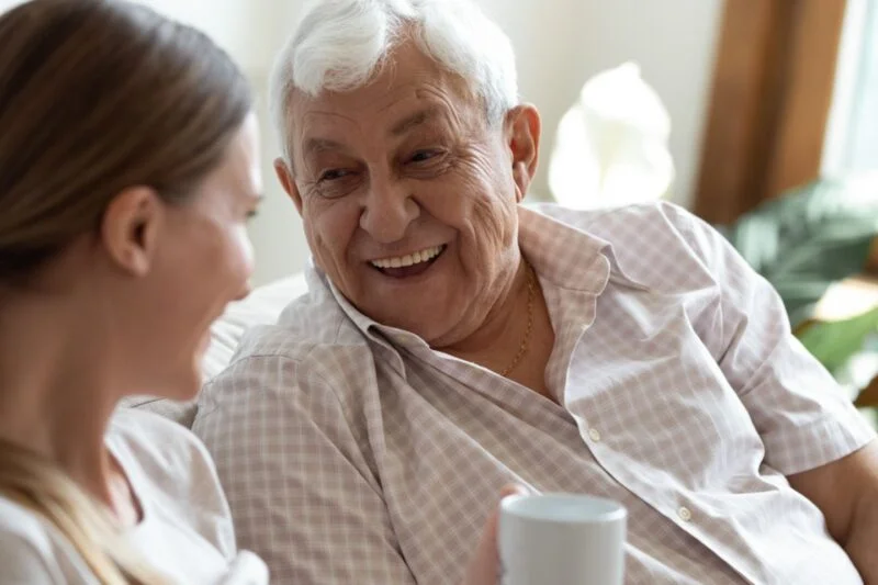 Smiling senior man talking with a caregiver at home, representing exceptional senior home care in Sun City Summerlin, Nevada