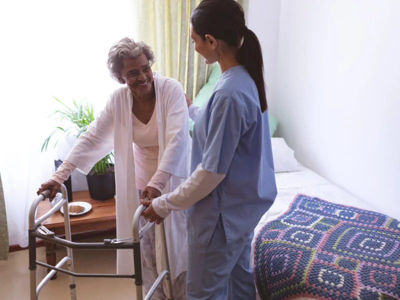 Caregiver assisting an elderly woman with a walker, providing attentive 24-hour home care