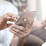 Senior using a smartphone with caregiver support, showcasing how home care technology helps seniors stay connected and independent