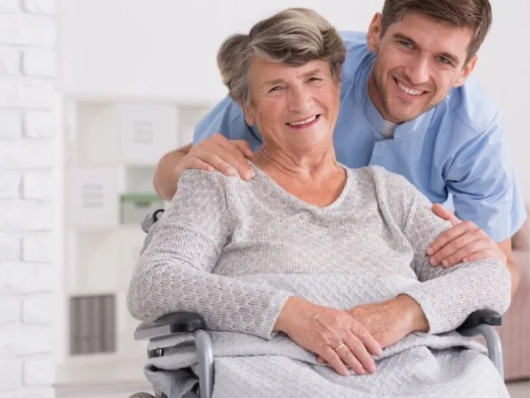 Caregiver supporting an elderly woman in a wheelchair during post-surgery recovery care at home