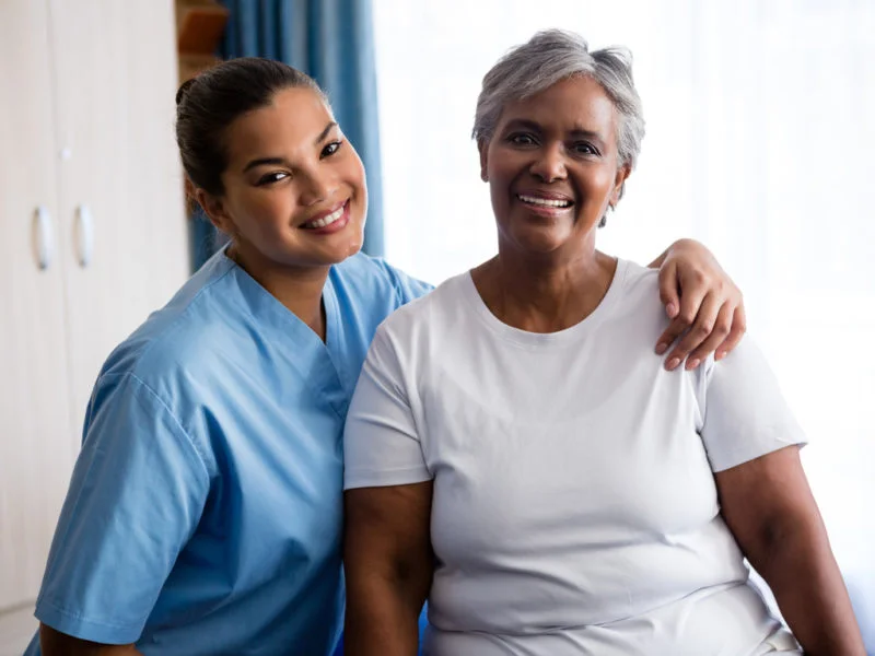 Professional caregiver standing beside a smiling senior woman, representing compassionate and reliable home care services